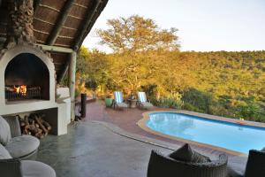 a swimming pool with a fireplace next to a house at Sibuya Game Reserve and Lodge in Kenton on Sea