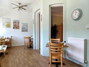 a dining room with chairs and a clock on the wall at By The Sea Bed and Breakfast in Eastbourne