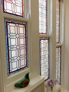 drie glas-in-loodramen in een kamer met een vaas bij By The Sea Bed and Breakfast in Eastbourne