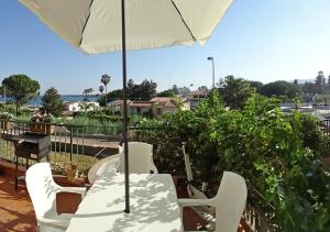 a table and chairs with an umbrella on a patio at Casa Roby 120 mt Beach in Fontane Bianche