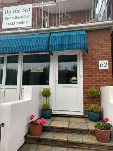 uma porta da frente de um restaurante com vasos de plantas em By The Sea Bed and Breakfast em Eastbourne