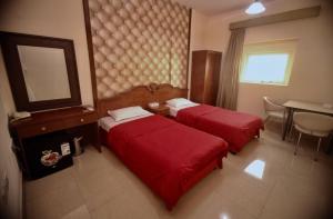 a hotel room with two beds and a table and a mirror at Emirates Plaza Hotel in Ajman 