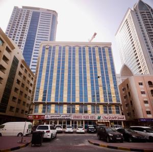 a large building with cars parked in a parking lot at Emirates Plaza Hotel in Ajman 