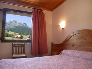 a bedroom with a bed and a window with a mountain at Hôtel Soleil des Neiges in Le Sauze +77 photos