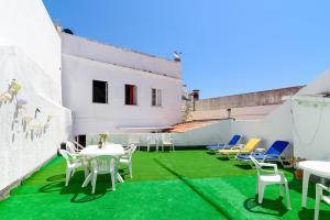a patio with green grass and white tables and chairs at Suntrap Hostel in Lagos