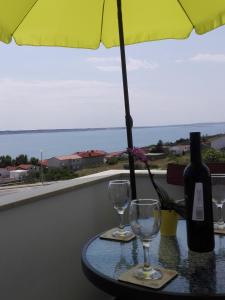 einen Tisch mit zwei Weingläsern und einem Regenschirm in der Unterkunft Apartment Marijan - Rtina in Rtina