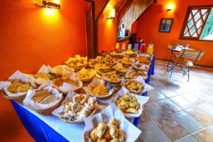 a long table filled with different types of bread and pastries at Pousada Ana Terra in Monte Verde