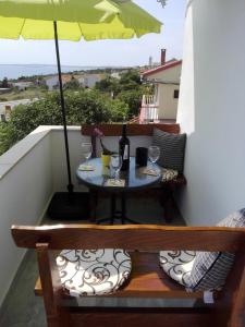 einen Tisch mit Weingläsern und einem Sonnenschirm auf dem Balkon in der Unterkunft Apartment Marijan - Rtina in Rtina