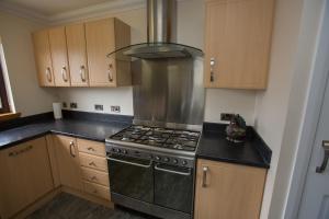 a kitchen with a stove top oven and wooden cabinets at GOLFVIEW 4 in Buckie +11 photos