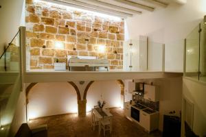 a large room with a stone wall and a kitchen at LA CARRETTERIA, ospitalità siciliana in Avola