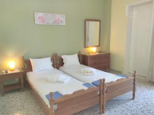 two beds in a room with two lamps and a mirror at Finikas Rooms in Agia Marina Aegina