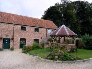 un edificio de ladrillo con un cenador delante de él en Wolds Village Hotel, en Bainton