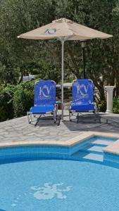 two blue chairs and an umbrella next to a pool at Kerveli Luxury Villa in Kerveli