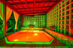 uma banheira laranja num quarto com luzes verdes em Pousada Ana Terra em Monte Verde