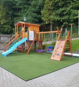 a playground with a slide and a play house at Domek nad Muszynką in Muszyna