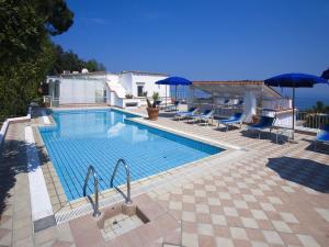 una grande piscina con sedie blu e ombrelloni di Hotel Villa D'Orta a Ischia