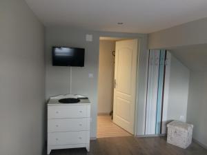 a room with a white dresser and a television on the wall at Báró Berg Apartman in Kapuvár