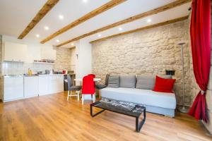 a living room with a white bed and a stone wall at Apartments Stinice in Gradac