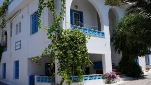 a white building with blue windows and a tree at Hotel Hara in Naxos Chora