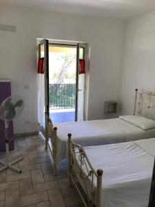 two beds in a room with a window and a door at Brigida's Apartments in Ipsos