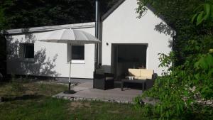 eine Terrasse mit einem Sonnenschirm, einem Sofa und einem Stuhl in der Unterkunft Cottage am Wald bei Berlin in Falkensee