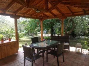a patio with a table and chairs under a wooden roof at House Christie in Chrysi Ammoudia
