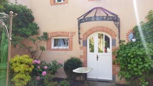 an entry to a house with an arch and a white door at Au Coq Bleu in Mareugheol
