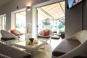 a living room with chairs and a table and windows at Hotel Aurora in Lignano Sabbiadoro
