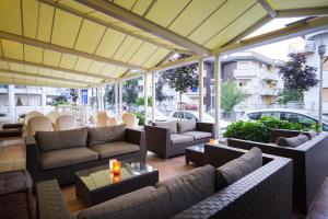een patio met banken, tafels en ramen bij Hotel Aurora in Lignano Sabbiadoro