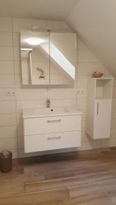 een witte badkamer met een wastafel en een spiegel bij Haus Kuhlmann in Altenau