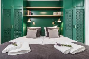 a green bedroom with a large bed with towels on it at Moss Apartment in Krakow