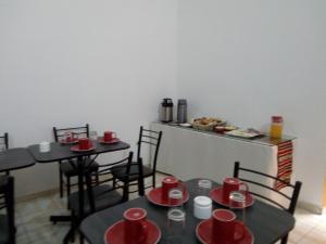 un comedor con 2 mesas y sillas con tazas rojas en Peru Swiss Hostel, en Arequipa