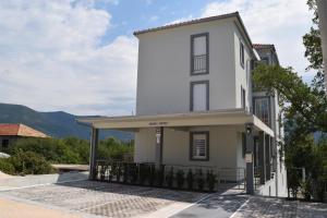 a white house with a balcony and mountains in the background at Kristina Apartments in Tivat
