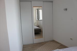 トルステノにあるApartments Platanaの鏡付きのベッドルーム1室、ベッド1台が備わるベッドルーム1室を提供しています。