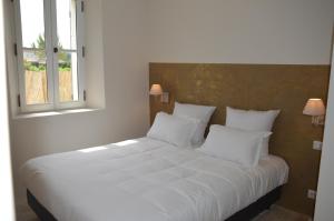 a white bed in a room with two windows at Les Gîtes Du Clos D'Olea in Oppède