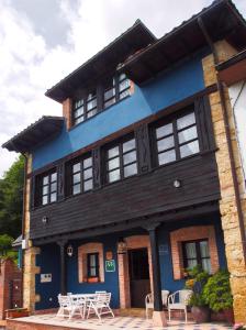 a blue building with white tables in front of it at Casas Rurales Asturias Campon Antrialgo in Infiesto