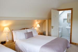 1 dormitorio con 1 cama blanca grande y baño en Mourneview B & B en Carlingford
