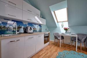 cocina con armarios blancos, mesa y sillas en Apartament Baltic Star Rewal, en Rewal
