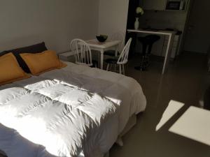 1 dormitorio con 1 cama blanca, mesa y sillas en La Suitte, en Bahía Blanca
