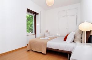 a white bedroom with a bed and a window at Sweet Garden in Cascais - Checkinhome in Cascais