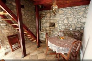 a dining room with a table and a stone wall at Holiday Home Banalu in Jadranovo