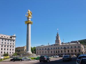 a large pole with a statue in front of a building at Sweet Home Freedom Square in Tbilisi City