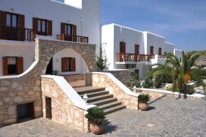 a row of white buildings with stairs and palm trees at Eri Hotel in Parikia
