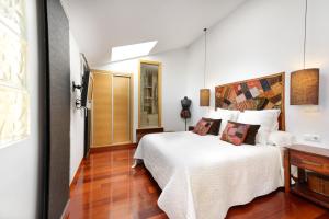 een slaapkamer met een wit bed en een houten vloer bij Boutique Penhouse in the City Old Town in Alicante