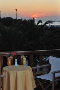 a table with two glasses on it with the sunset at Eri Hotel in Parikia