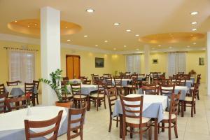 a dining room with white tables and wooden chairs at Eri Hotel in Parikia