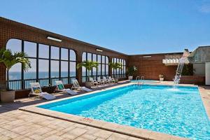 uma grande piscina com cadeiras e um edifício em Pasargada Praia da Costa em Vila Velha