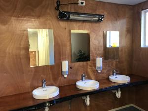 a bathroom with three sinks and two mirrors at Tongariro Holiday Park in Tongariro