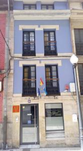 un edificio azul con ventanas y una bandera en Apartamentos Entrepalacios, en Avilés