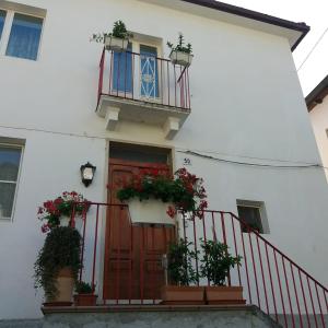 una casa bianca con porte rosse e piante in vaso di Casa Fermina a 5 minuti da Sulmona a Introdacqua